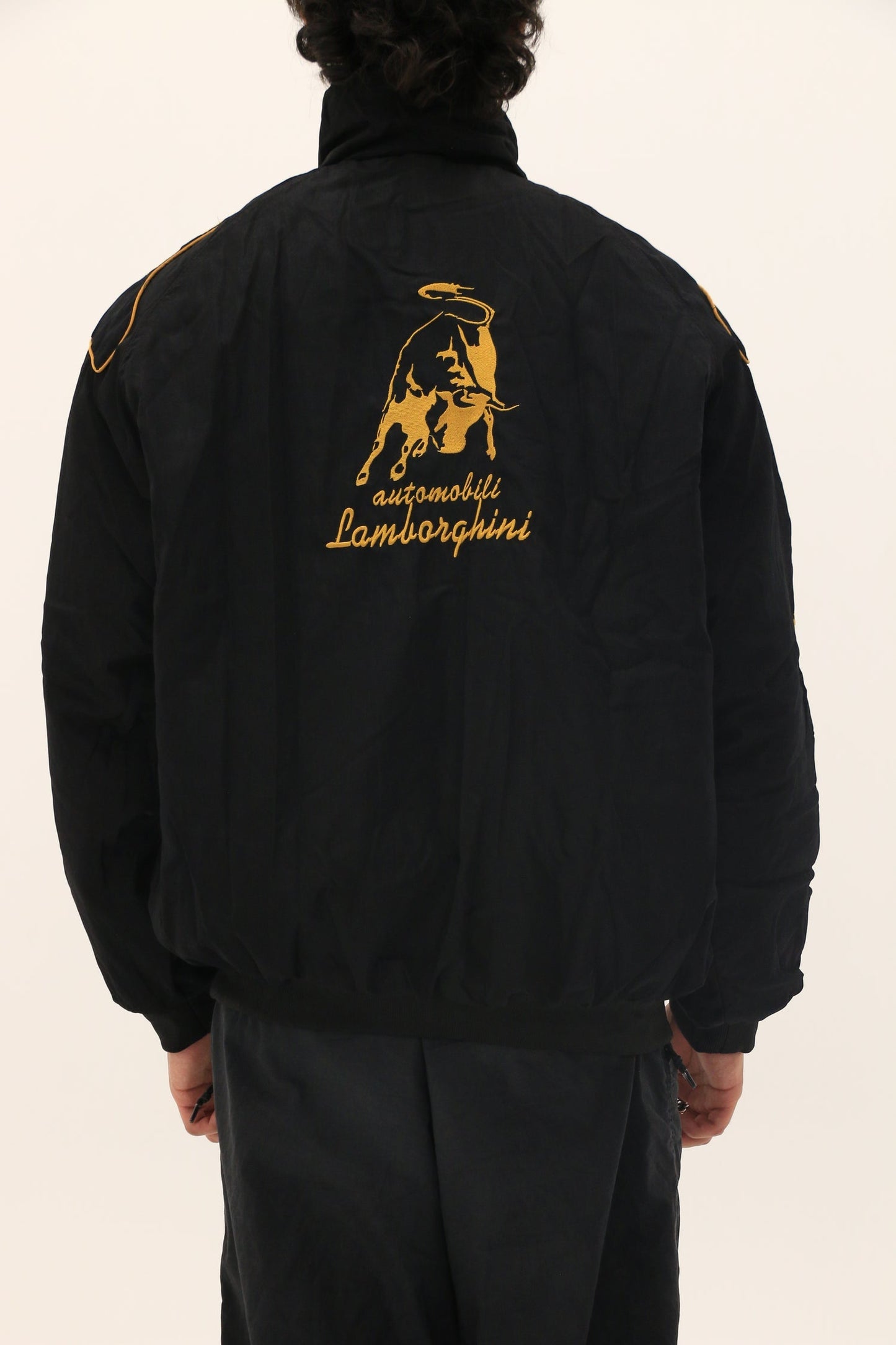 Black jacket with Lamborghini logo on the back against a beige background