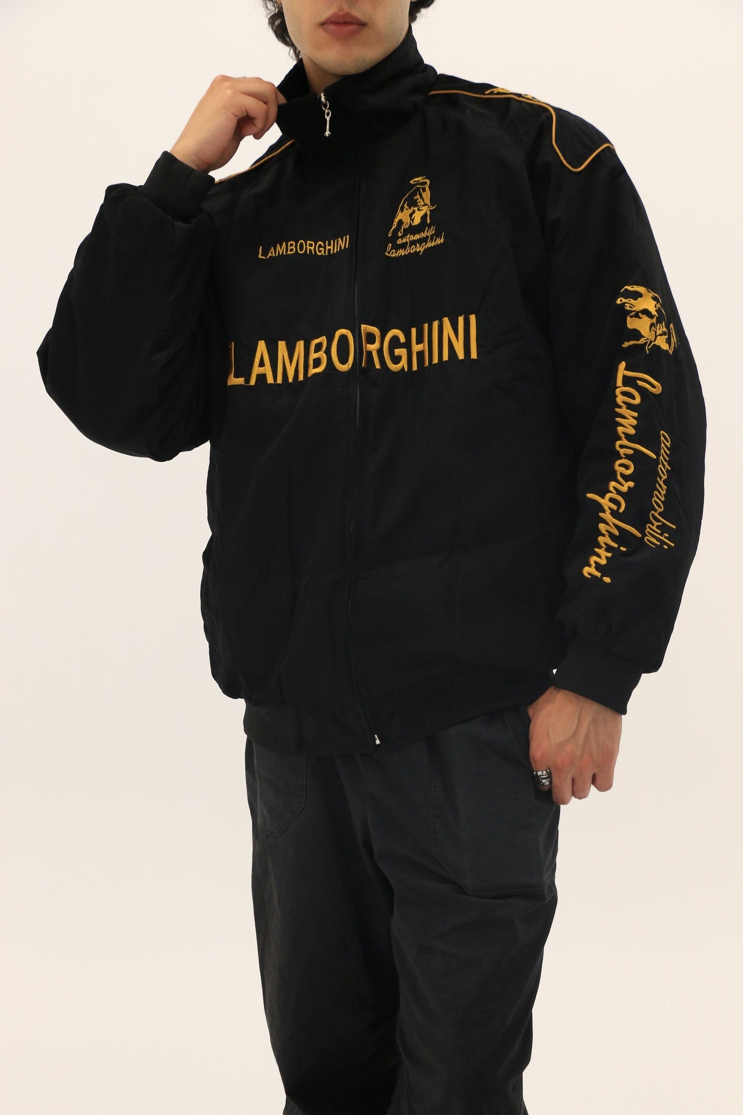 Male Model wearing a black Lamborghini tracksuit with gold text on a plain background